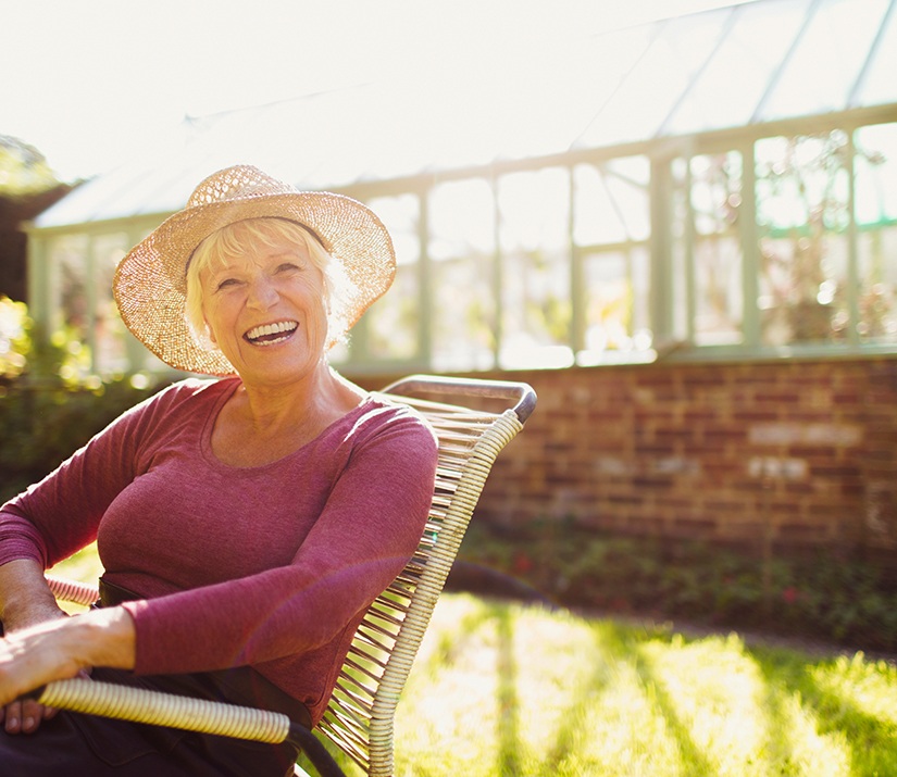 Senior woman with straw hat sitting in lawn chair and smiling