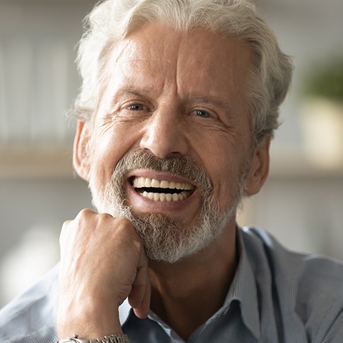 Senior man smiling while resting chin on fist