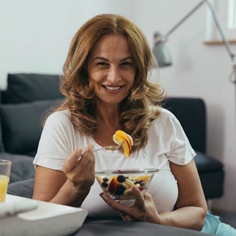 Woman with dental bridge in Brookfield eating fruit salad