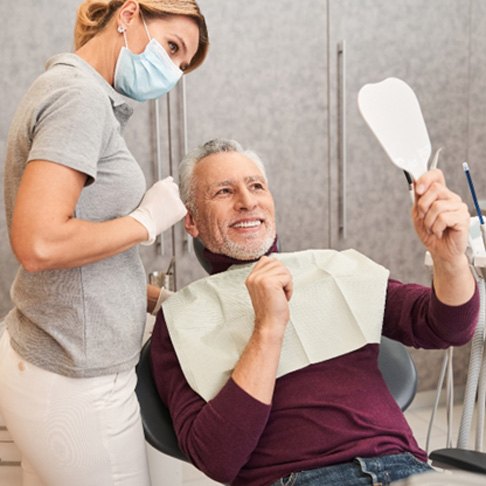 Patient smiling into mirror next to cosmetic dentist in Brookfield