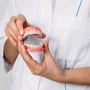 Dental professional holding upper and lower dentures