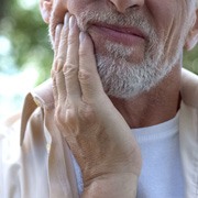 Older bearded man rubbing jaw due to tooth pain