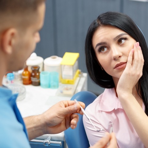 Woman holding cheek during emergency dentistry visit
