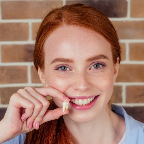 Woman holding up wisdom tooth after extraction