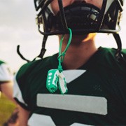 Closeup of green and white mouthguard hanging from football helmet