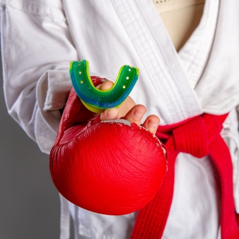 Person with boxing gloves holding an athletic mouthguard