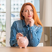 a woman putting a coin into a piggy bank