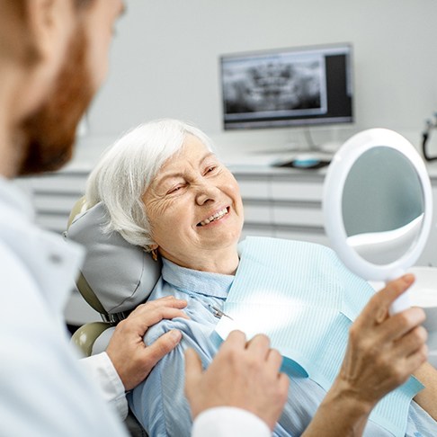 An elderly woman admiring her new dental implants