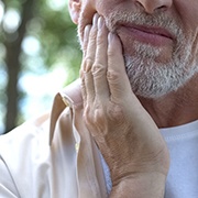 An older man having side effects from dental implant placement