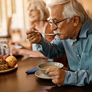 An older man having soup as a meal
