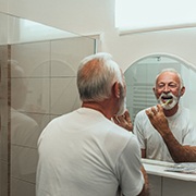 An older man brushing his teeth in the bathroom