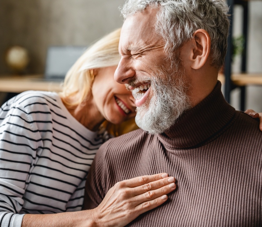 Man and woman with dental implants smiling