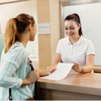 Dental team member taking Medicaid forms from dental patient