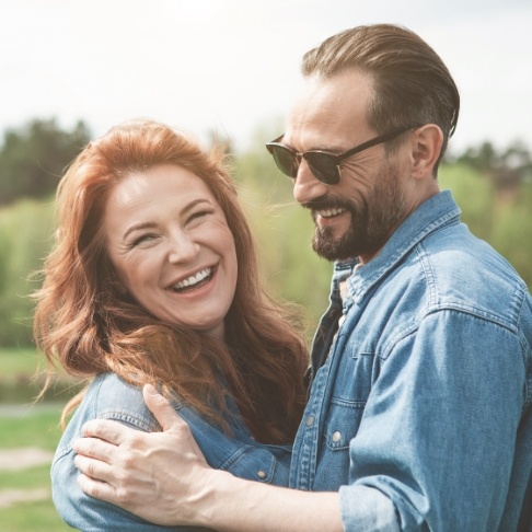 Man and woman smiling after full mouth reconstruction