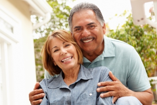 Man and woman with complete smiles after dental implant tooth replacement